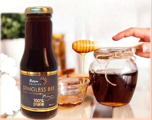 Bottle of Bayu Stingless Bee honey with a jar being filled with honey.